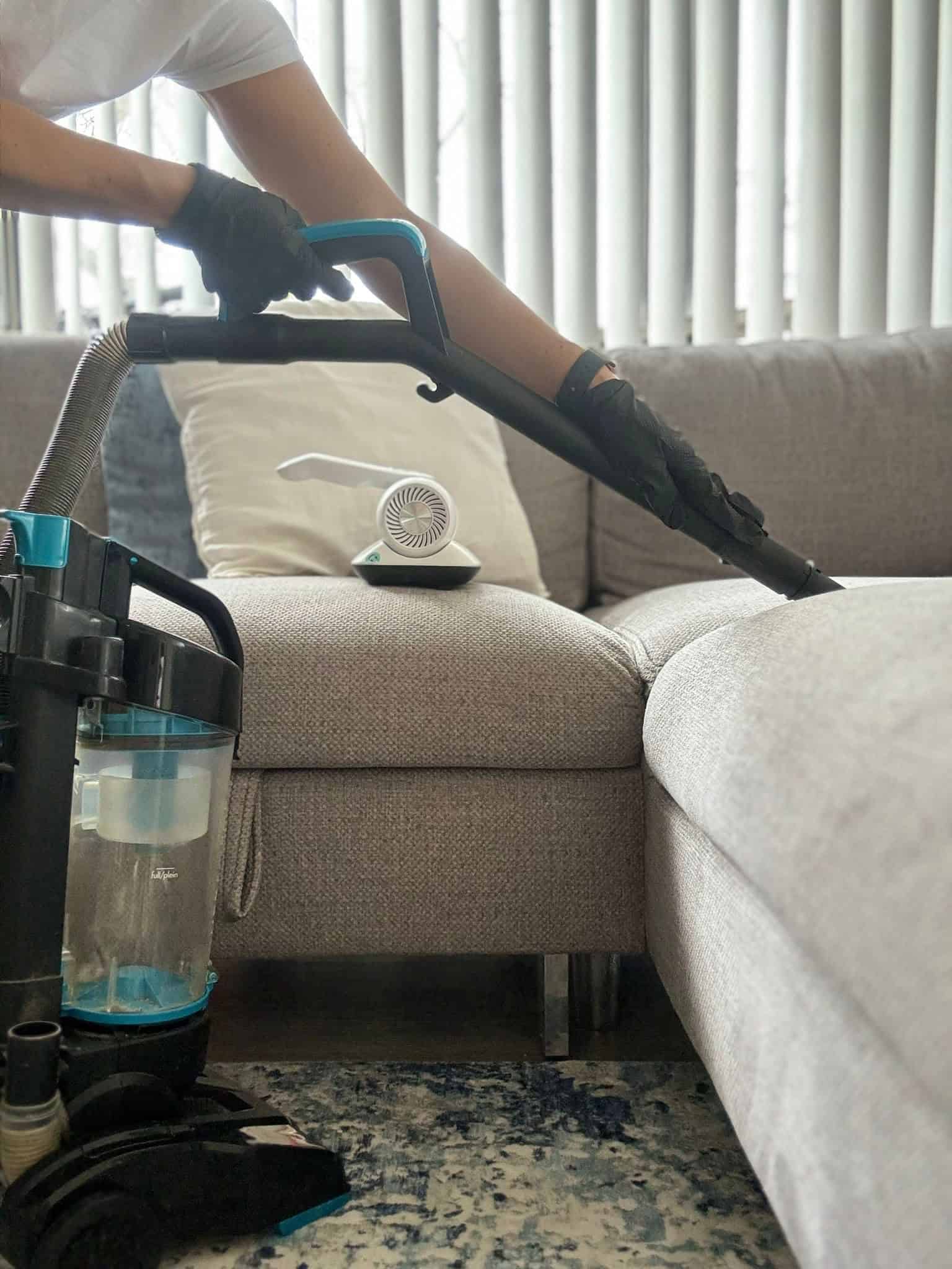 Couch cleaning in progress with a vacuum cleaner, highlighting thorough upholstery cleaning by KC Ho.